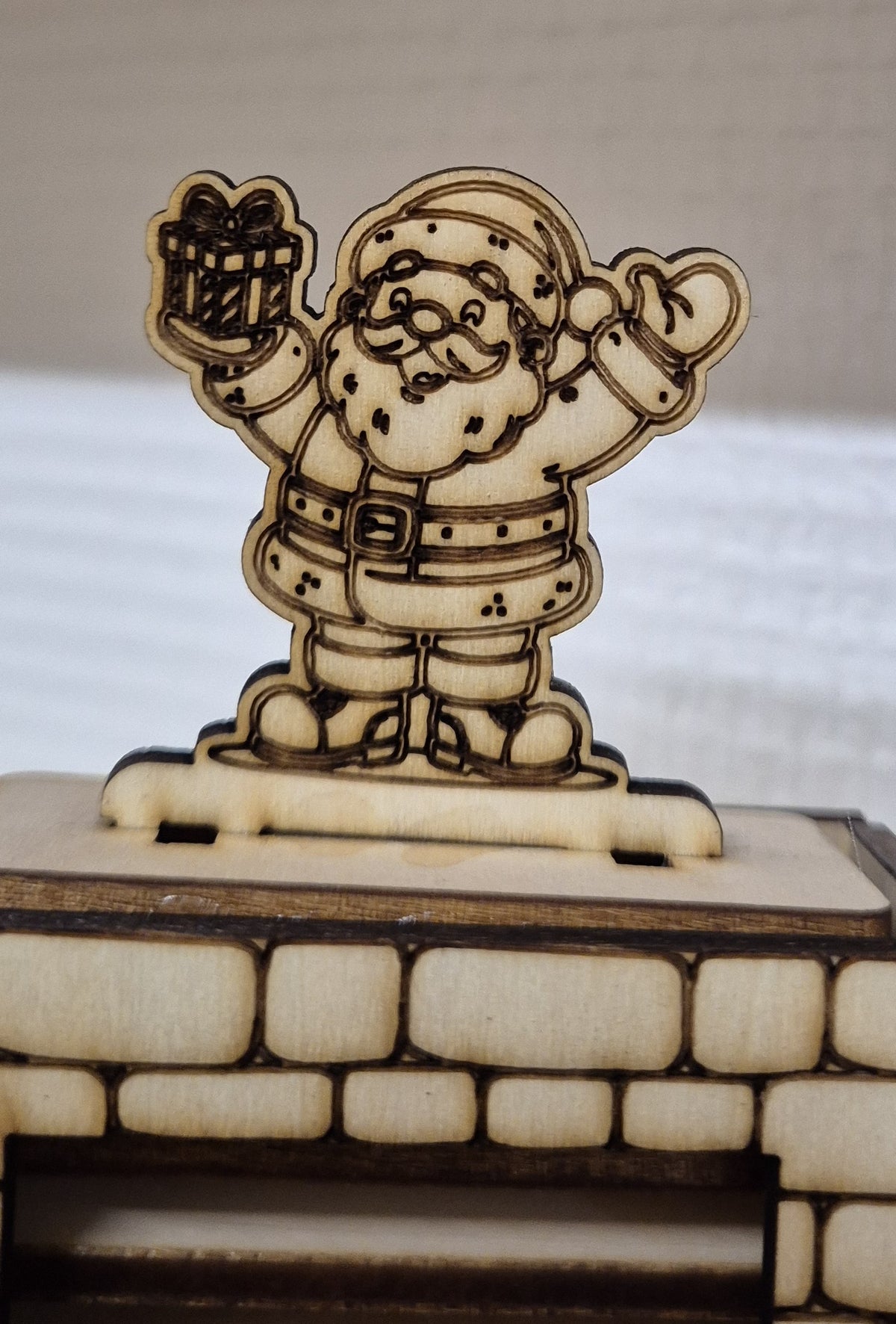 Nærbillede af julemanden med gave øverst på julekalenderens skorsten.